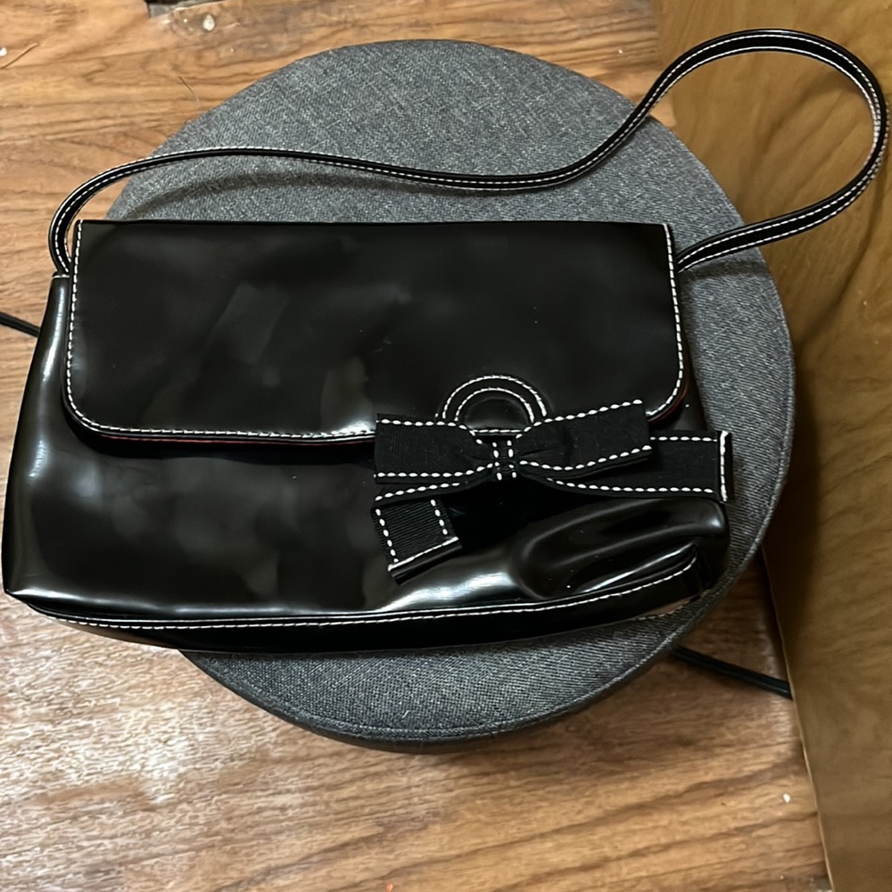 Victoria Secret black bag with a bow on the front  and a snap to close.